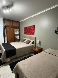 um quarto com duas camas e uma pintura vermelha na parede em Suíte no castelo flat no Home Green Home em Campos do Jordão