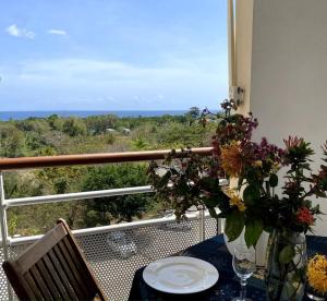 - une table avec un vase de fleurs sur le balcon dans l'établissement Appartement - Vue mer et montagne, à Sainte-Luce