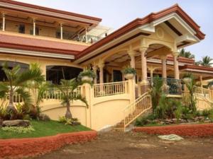 a large house with a balcony with plants on it at Camiguin Highland Resort in Mambajao