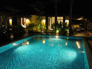 a large blue swimming pool at night with lights at Chidlom Resort in Haad Chao Samran