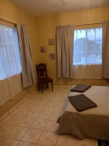 a bedroom with two beds and a chair and windows at Hill Top Villa (HTV) in Bridge Pen