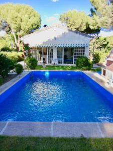 une grande piscine bleue en face d'une maison dans l'établissement Chalet con piscina El Refugio de Venecia, à El Campillo