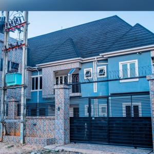 una casa de ladrillo azul con techo negro en Jimms Place en Owerri