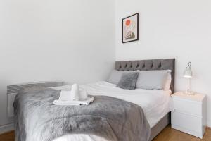 een witte slaapkamer met een groot bed met witte lakens bij Spacious Studio High Street Location in Londen