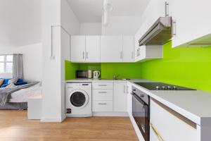 a kitchen with white cabinets and a green wall at Spacious Studio High Street Location in London
