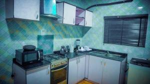 a small kitchen with a stove and a microwave at Jimms Place in Owerri