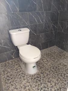 a white toilet in a bathroom with black tiles at El paraíso de Zacatlán, Departamento con Terraza, 10 pax in Zacatlán