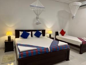 a bedroom with two beds with blue and red pillows at Sigiri Hibiscus Villa in Sigiriya
