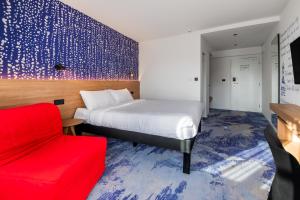 ロジュノフ・ポト・ラドホシュチェムにあるibis Styles Relax Roznov pod Radhostemのベッドと赤い椅子が備わるホテルルームです。