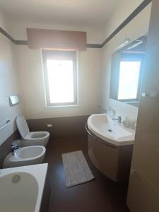 a bathroom with a toilet and sink and two windows at Vista Monte Retreat in Reggio Calabria