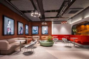 une salle d'attente avec des tables, des chaises et des photos sur le mur dans l'établissement Scandic Nürnberg Central, à Nuremberg