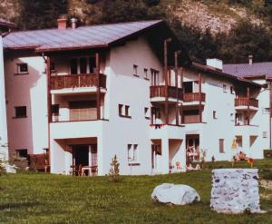 ein großes weißes Gebäude mit Balkonen auf einem Feld in der Unterkunft Ferienwohnung in Savognin in Savognin