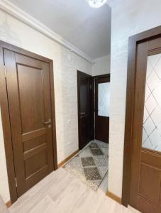 pasillo con 2 puertas marrones y suelo de baldosa en 12 Microragion Apartments, en Aktobe