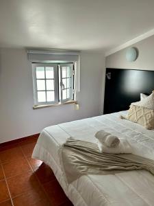 Alojamento S. João في بينيش: غرفة نوم مع سرير أبيض كبير مع نافذة