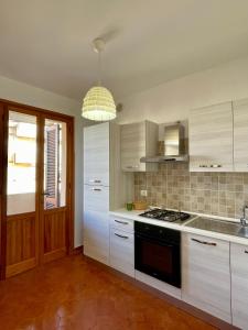 uma cozinha com armários brancos e um forno com placa de fogão em TALAhome27 em Alghero