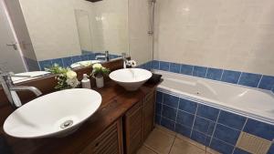 een badkamer met 2 wastafels en een bad bij Bienvenue chez Maxime in Saint-Denis