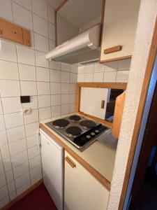 a small kitchen with a stove and a sink at Appartement Eskival skis aux pieds in Val Thorens +22 photos
