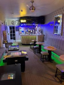 um restaurante com mesas e um bar com luzes roxas em Clifton Private Hotel em Blackpool