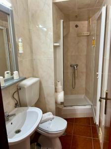 a bathroom with a toilet and a sink and a shower at Alojamento S. João in Peniche