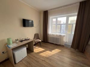 a room with a desk and a television and a window at Belon inn in Astana