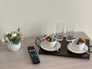 a table with two tea cups and a remote control at Belon inn in Astana