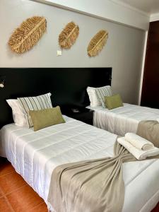 two beds in a room with baskets on the wall at Alojamento S. João in Peniche