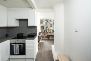 a kitchen with white cabinets and a stove at Ideal 1BD Flat Shoreditch For City Explorers in London