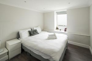 a white bedroom with a large bed with a window at Ideal 1BD Flat Shoreditch For City Explorers in London