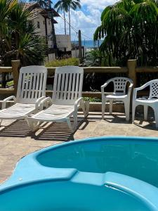 three white chairs sitting next to a swimming pool at Princesinha do Sul in Ilhéus