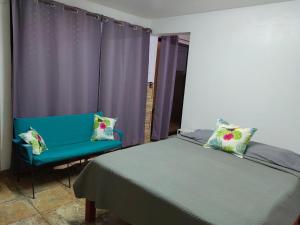 a bedroom with a bed and a blue chair at Casa Victoria in Puntarenas