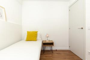 Dormitorio con cama con almohada amarilla en Picasso Suites Cornellá 2.2 en Cornellà de Llobregat