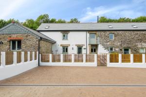 uma casa de tijolos com uma cerca de madeira e uma entrada em The Granary em Camelford