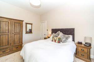 1 dormitorio con 1 cama blanca grande y armario de madera en Montgomery Large 2 Bedroom Flat - 5 Mins Walk to City Centre en Edimburgo