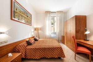 Habitación de hotel con cama, escritorio y escritorio. en Hotel Minerva, en Siena