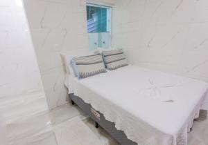 uma cama branca num quarto com uma janela em Home Superior Nascer do Sol em Cairu