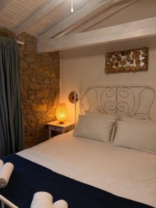 a bedroom with a white bed with a stone wall at Kalyopi Köy Evi in Gokceada Town