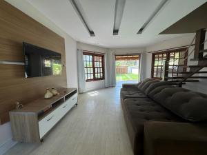 Il comprend un salon doté d'un canapé et d'une télévision à écran plat. dans l'établissement Casa encantadora a 100 m da praia de Geribá - WIFI 200MB - TV Smart - 5 Quartos - Garagem - Cozinha equipada - Churrasqueira, à Búzios