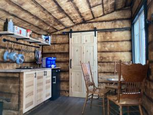 een keuken met houten wanden en een tafel en stoelen bij Your Cozy Cabin Retreat in Saint-Rémi-dʼAmherst