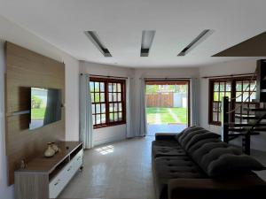 - un salon avec un canapé et une télévision dans l'établissement Casa encantadora a 100 m da praia de Geribá - WIFI 200MB - TV Smart - 5 Quartos - Garagem - Cozinha equipada - Churrasqueira, à Búzios