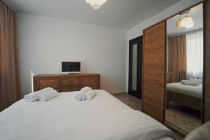 Schlafzimmer mit einem weißen Bett und einem TV in der Unterkunft Luxury Apartament Ultracentral of Suceava Esplanada in Suceava