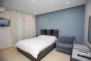 a bedroom with a bed and a blue chair at Sale e Sole Rooms in Vlorë