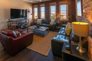 a living room with leather furniture and a brick wall at Charming Savannah Penthouse: Grand Views & Dual Parking in Savannah