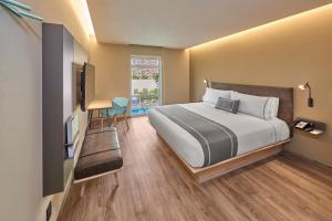 - une chambre avec un grand lit et une télévision dans l'établissement City Express Plus by Marriott Ensenada, à Ensenada