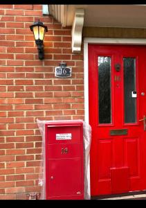 czerwone drzwi i czerwona skrzynka pocztowa obok ceglanego budynku w obiekcie Quaint and Serene Single room w Londynie