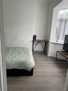 a white bedroom with a bed and a table at High street home in Eastleigh