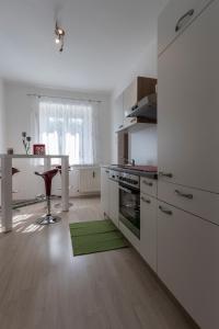 cocina con armarios blancos y alfombra verde en Flataid Apartment Elisabethinergasse, en Graz