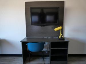 a desk with a tv and a blue chair at Hilltop Express Inn in Groton