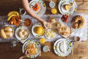 a table filled with plates of breakfast foods at Suítes em Cabo Frio in Cabo Frio