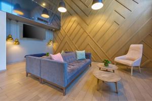 - un salon avec un canapé bleu et deux chaises dans l'établissement City Express Plus by Marriott Periferico Sur Tlalpan, à Mexico