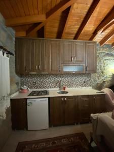 una cucina con armadi in legno, piano cottura e lavandino di Kalyopi Köy Evi a Gokceada Town